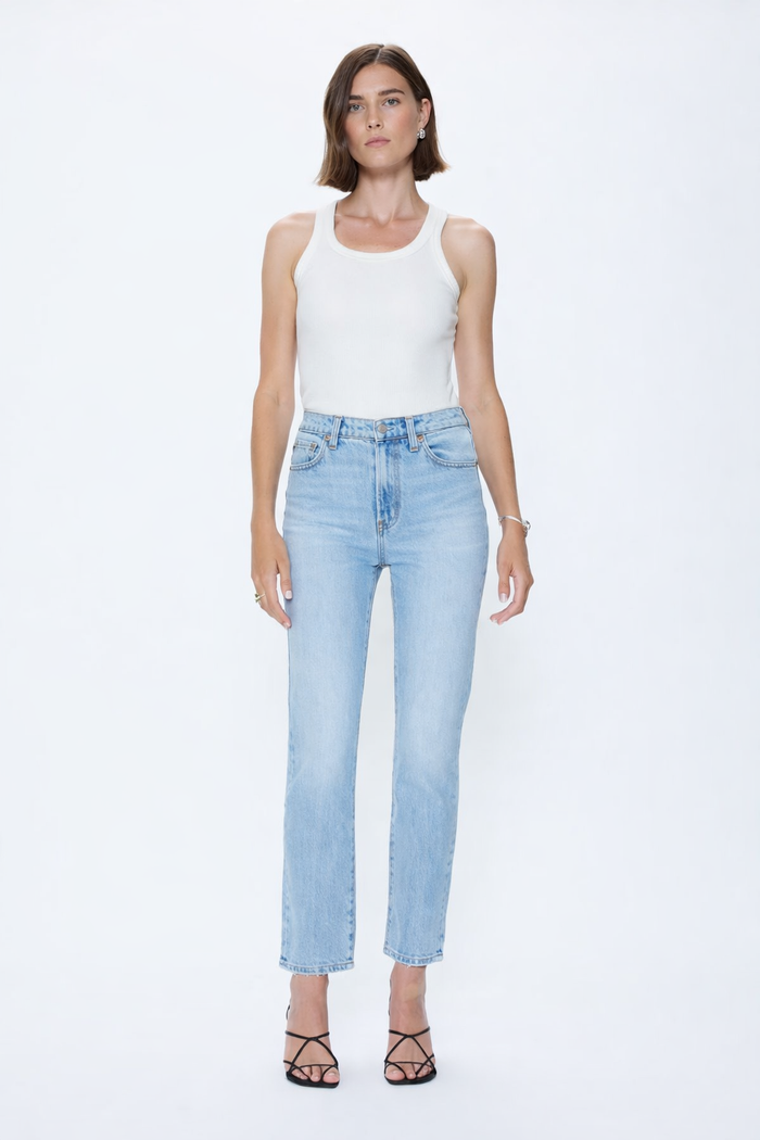Woman wearing a white tank top and light blue jeans on a white background