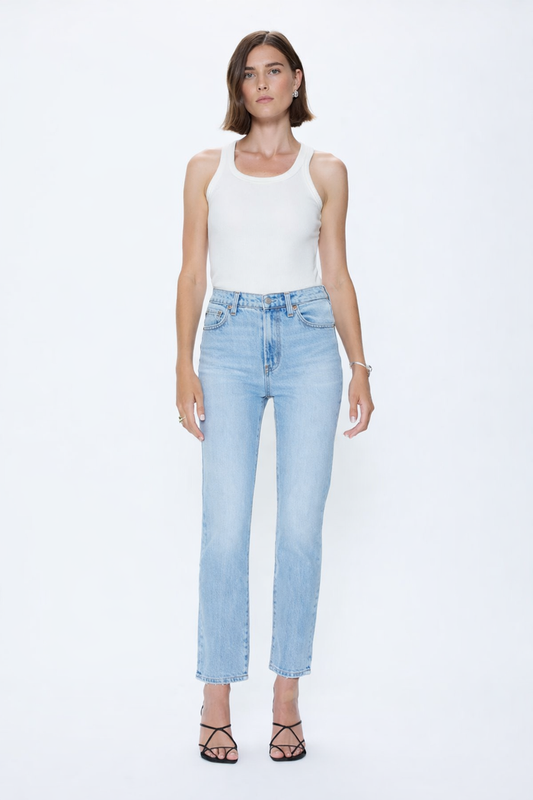 Woman wearing a white tank top and light blue jeans on a white background