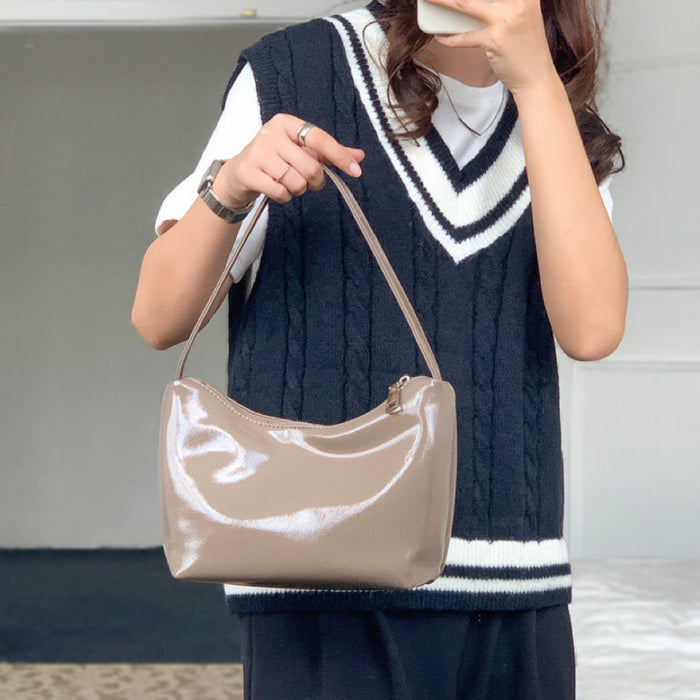 Model holding the khaki patent leather bag; sleek 90s hobo design ideal for urban daily use and office chic.