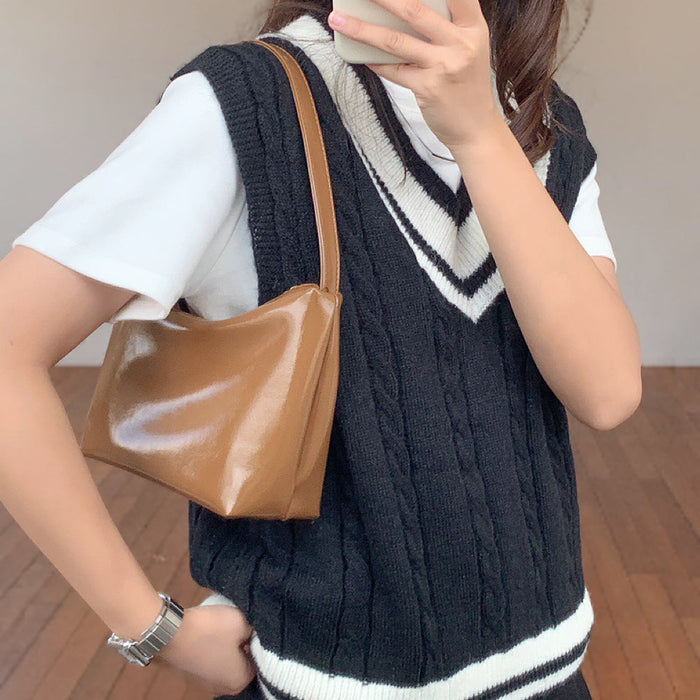 Model styling the camel leather shoulder bag; versatile neutral glossy accessory for autumn/winter outfits.