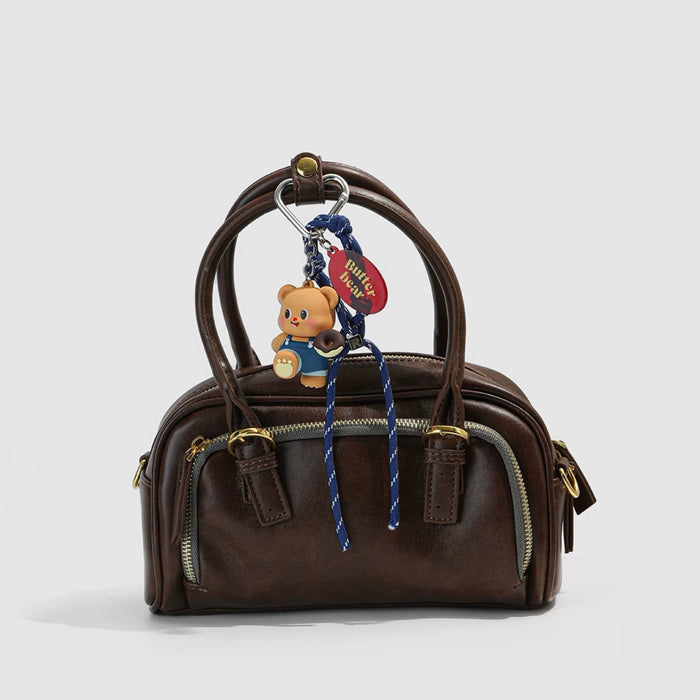 Front view of a brown handbag with blue Butter Bear Bag Charm.