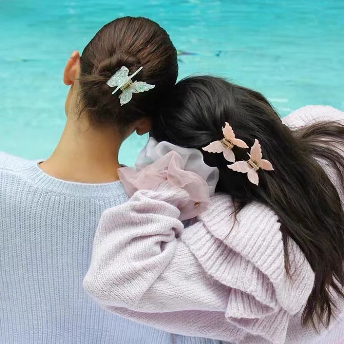 Two models wearing butterfly hair claw in pink and green, great for everyday styling and gifting.