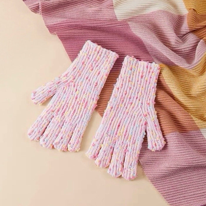 Pink candy-dot knit gloves with raised dot texture and ribbed cuffs, laid on a scarf; cozy winter styling.
