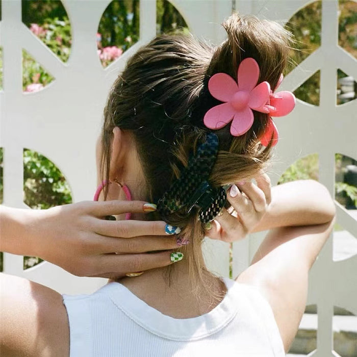 Model wearing a Pink acrylic flower hair claw, showcasing vacation style.