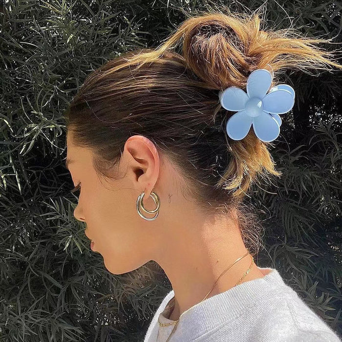Model wearing a Candy Flower Hair Claw in blue, ideal for quick updos and ponytails.