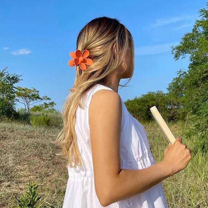 Model wearing a Candy Flower Hair Claw  in orange, easy for workdays and special occasions.