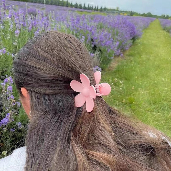 Model wearing a Candy Flower Hair Claw  in pink, great for everyday styling and gifting.