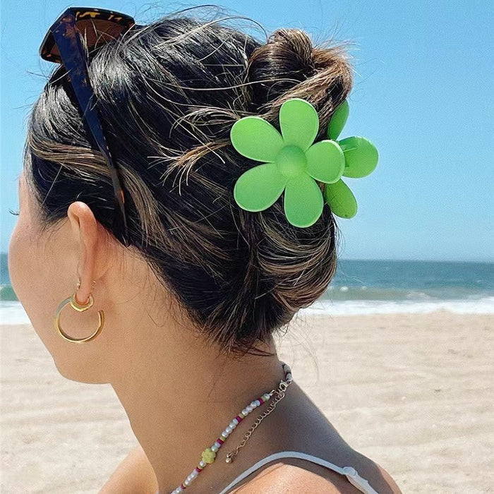 Model wearing a  Candy Flower Hair Claw in green, ideal for quick updos and ponytails.