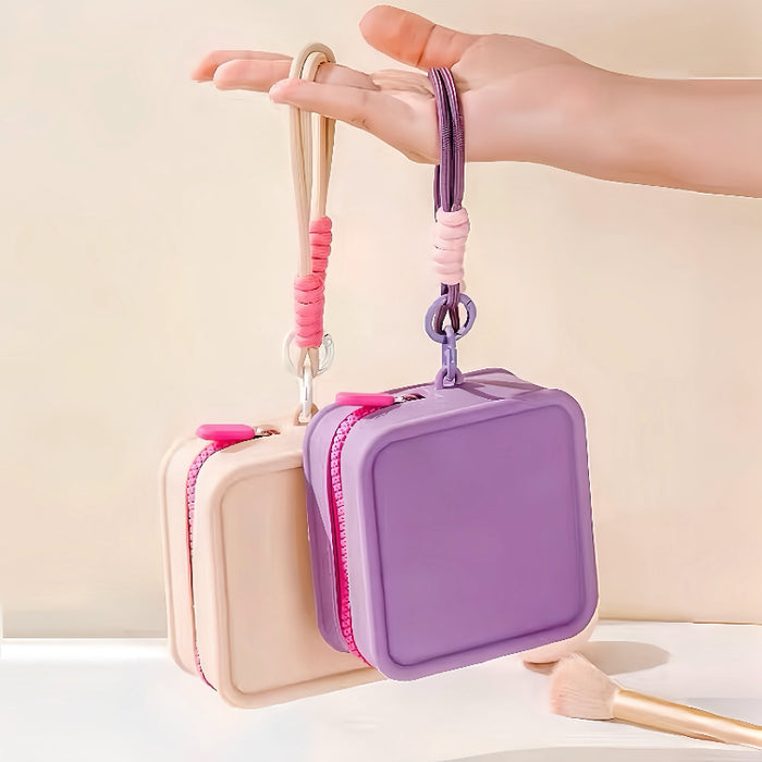Close-up of a hand holding the waterproof jelly makeup bag by its durable woven wristlet strap.