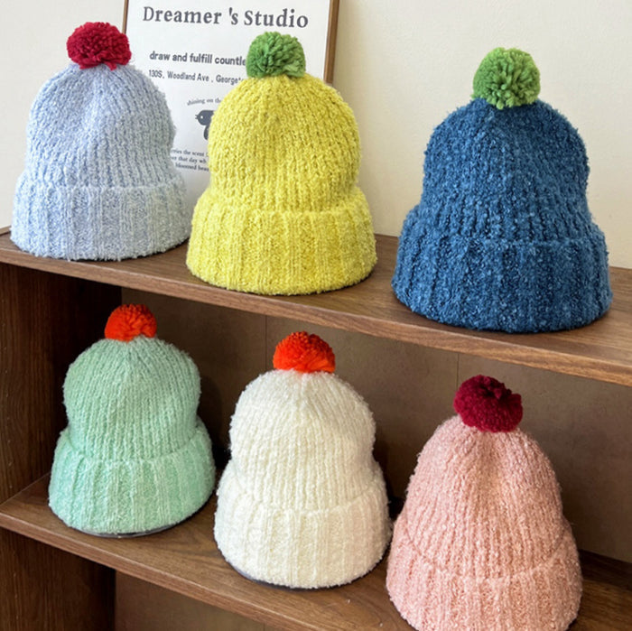 Six colorful knitted pompom beanies in blue, yellow, teal, mint, white, and pink shades.