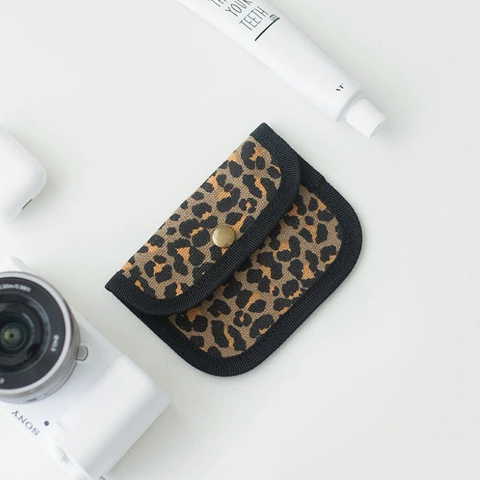 Leopard print canvas coin purse with black trim; snap-flap pouch for coins, lip balm, and small items.
