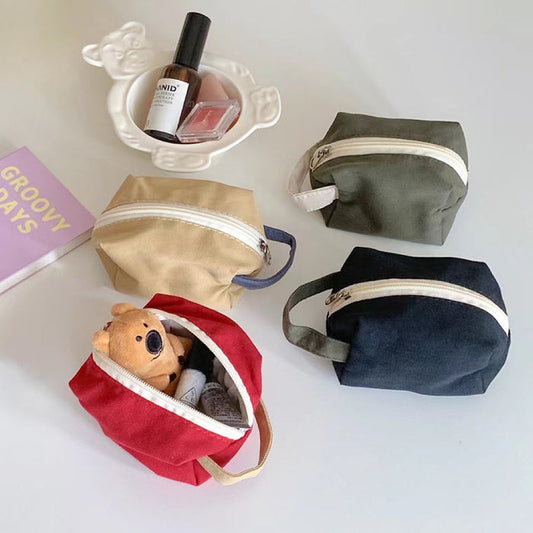 Four canvas makeup bags in red, olive green, khaki, and black; durable travel cosmetic organizers in two sizes.