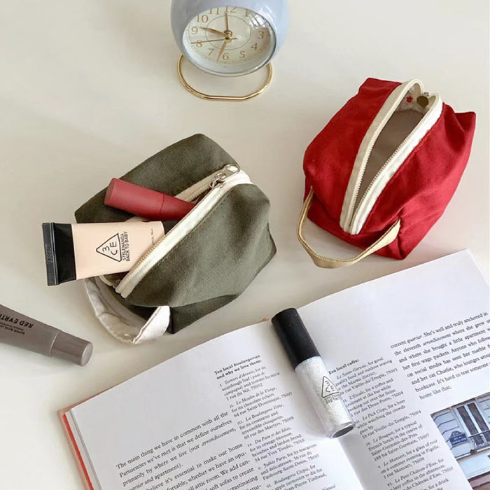 Close-up of green and red canvas toiletry bags; showcasing the sturdy canvas texture and zipper.