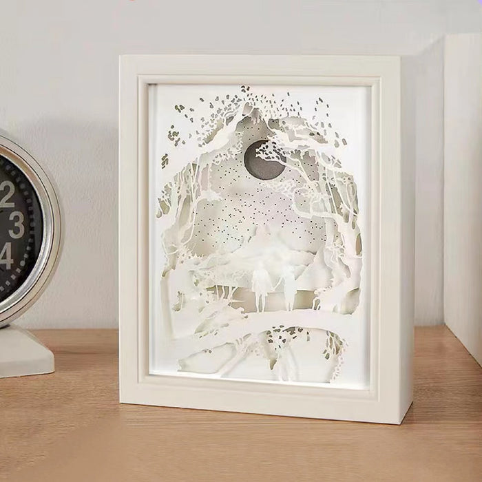 Front view of White carved paper lamp with intricate layered forest and moon design.