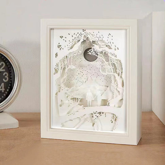 Front view of White carved paper lamp with intricate layered forest and moon design.
