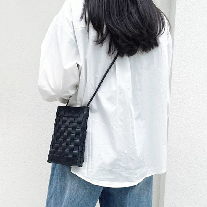 Model carrying a black asssette woven bag as crossbody, easy for commuting and weekends.