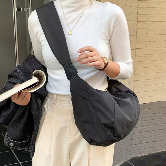 Black padded bag worn crossbody, highlighting its lightweight build for daily commutes.