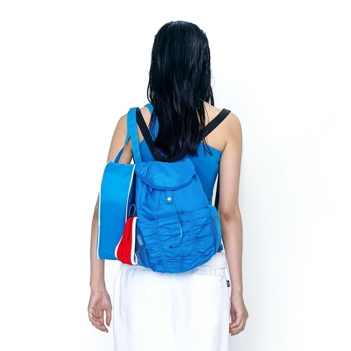 Model wearing the blue pleated backpack; vibrant aesthetic perfect for active urban lifestyle and street styling.