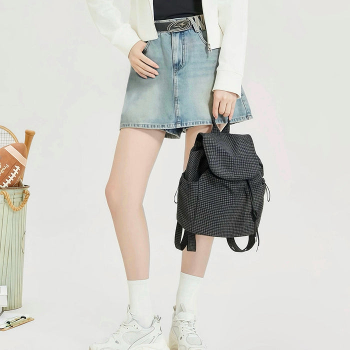 Model carrying a  black Check Mate Mini Backpack handheld, ideal for city walks and gifting.