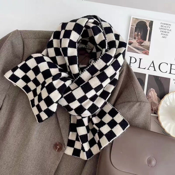 Angled view of Black and white checkerboard wool blend scarf draped over a brown blazer, easy for travel.