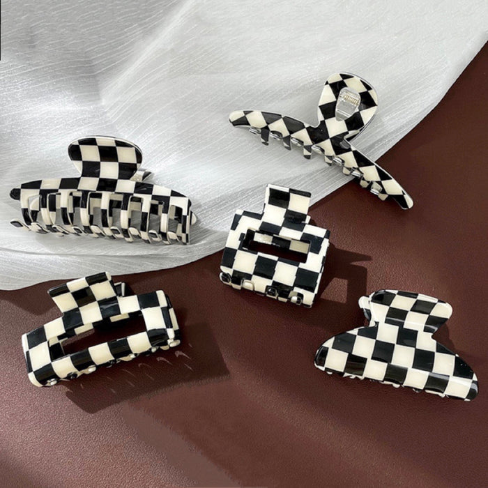 Flat lay of five black and white checkerboard acrylic hair claws in various sizes and shapes.