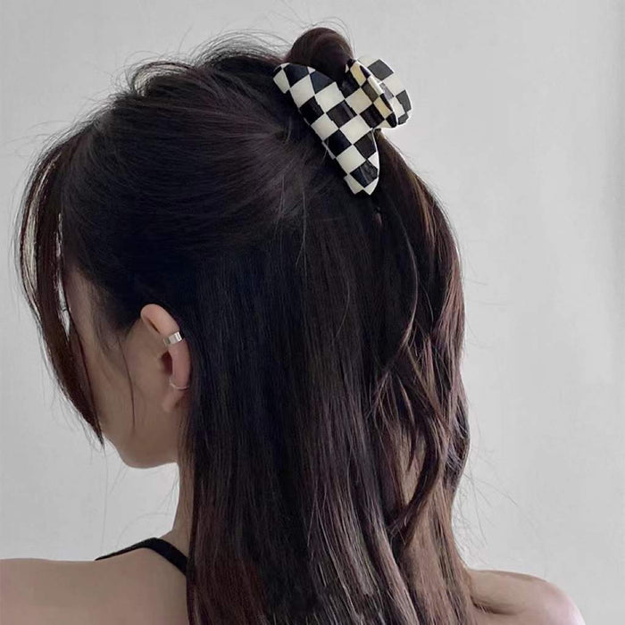 Model wearing checkerboard hair claw in curve shape, great for everyday styling and gifting; for office.