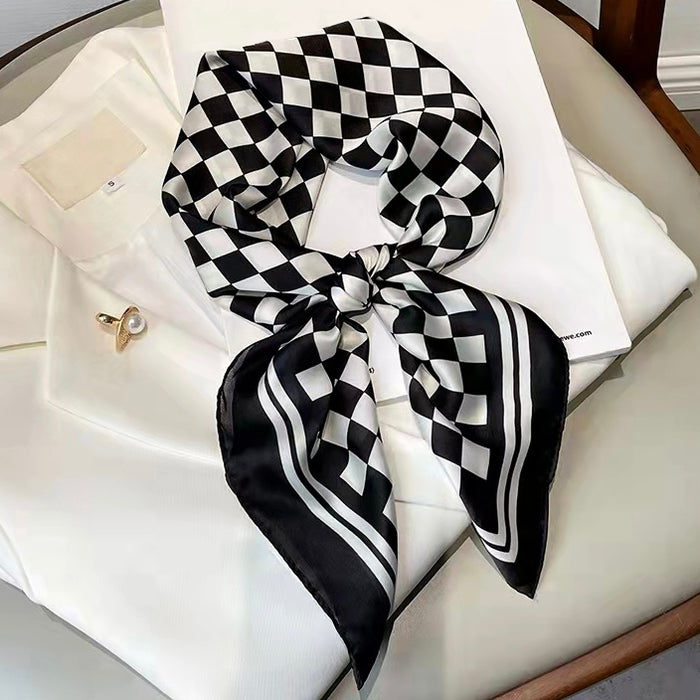 Close-up of the black and white square scarf tied elegantly around a white garment.
