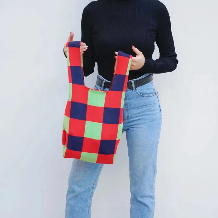 Model carrying a red plaid tote bag handheld, easy for commuting and weekends.