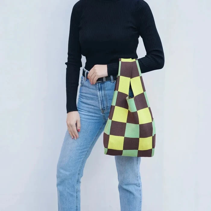 Model carrying a green plaid tote bag handheld, great for daily carry and travel.