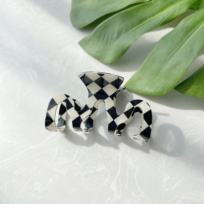 Close-up of checkered hair claw in mcross shape, easy for workdays and special occasions.
