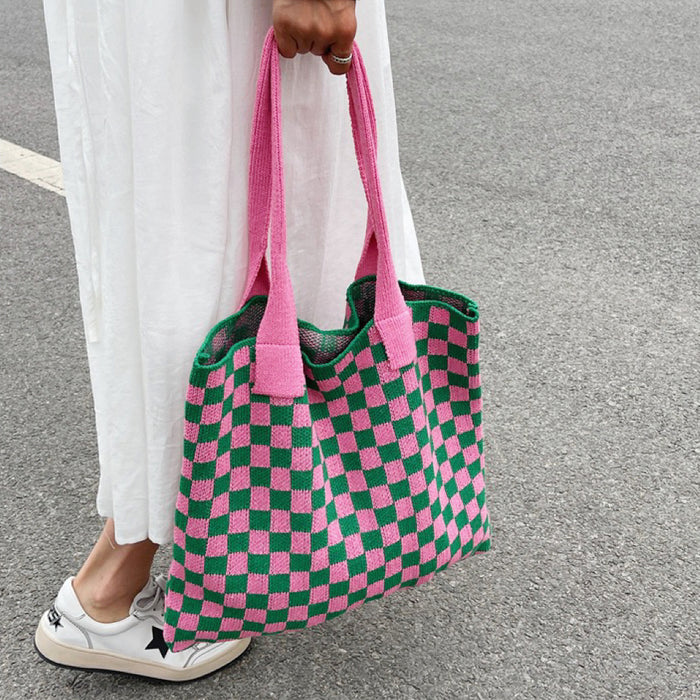 Handheld view of the pink and green checkered knit bag, showcasing its flexible casual shape.