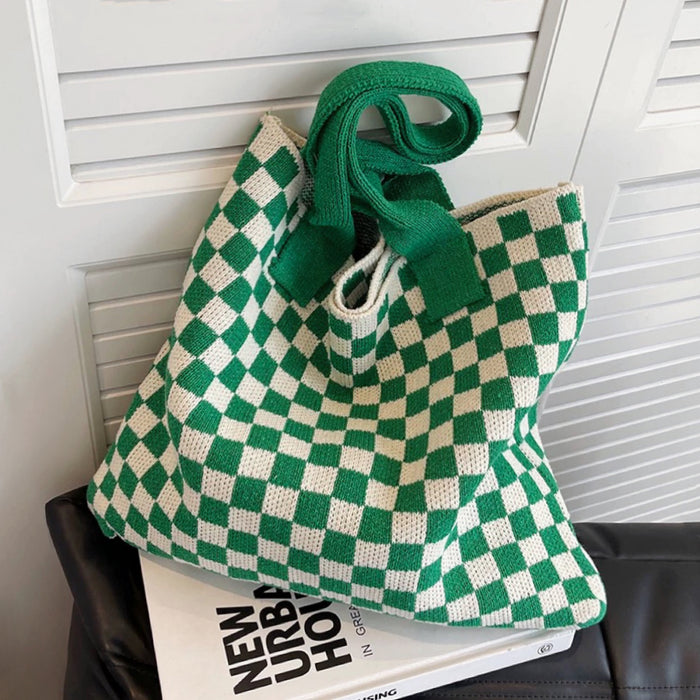 Green and white checkerboard knit tote placed on a magazine, highlighting its trendy aesthetic.