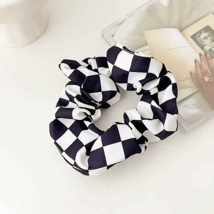 Angled view of checkerboard satin scrunchie in black, ideal for quick updos and ponytails.