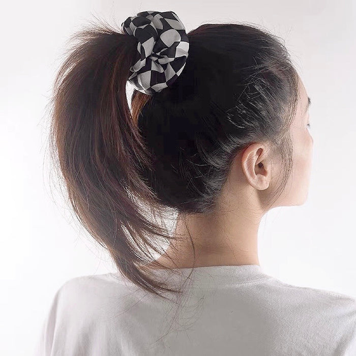 Model wearing checkerboard satin scrunchie in black, easy for workdays and special occasions.