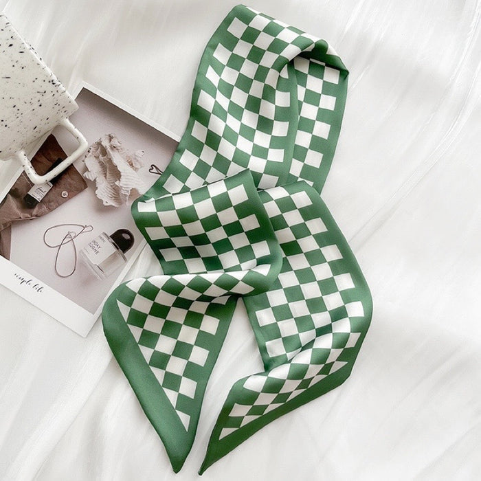 Angled view of Green and white checkered silk-like skinny scarf on a white surface.