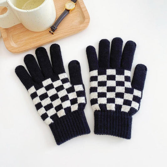 Flat lay checkerboard knitted touch screen gloves in black and white with ribbed cuffs; cozy for winter phone use.