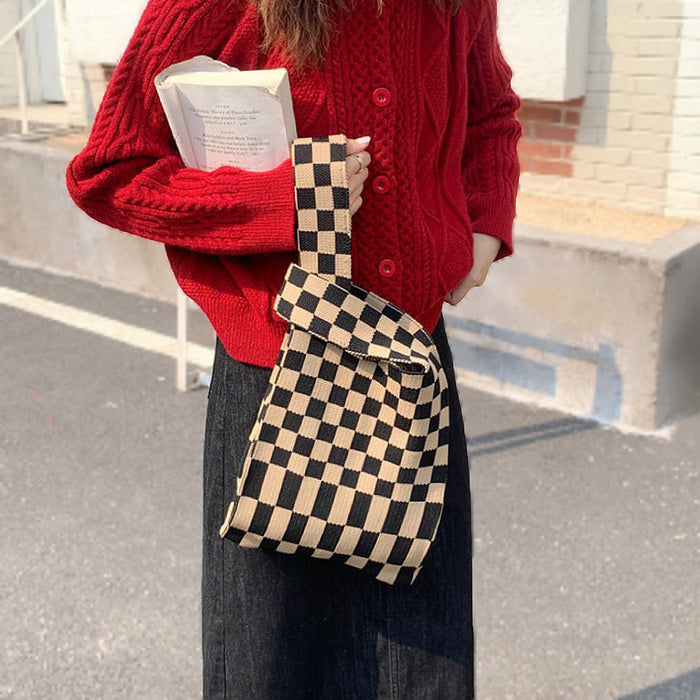 Model wearing a black and coffee checkered woven tote bag with a red cardigan.