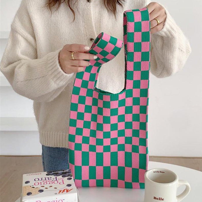Model holding a vibrant pink and green checkered woven tote bag.