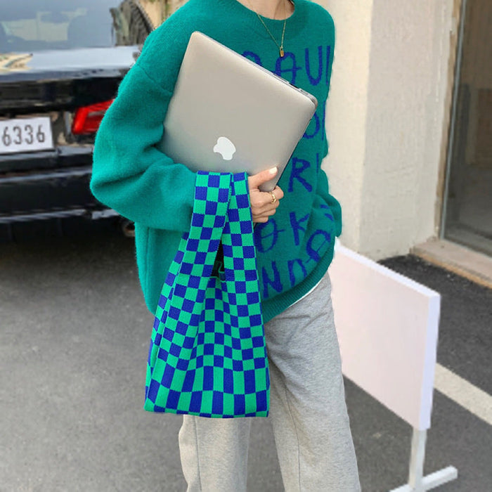 Model carrying a bright blue and green checkered woven tote bag.