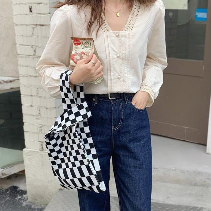 Model wearing a classic black and white checkered woven tote bag.