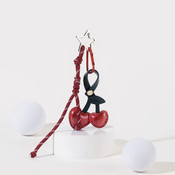 Angled view of Cherry Bag Charm with cherry and rope, easy to attach to bags and phones.