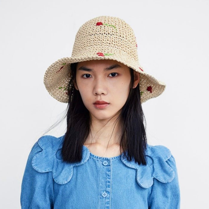 Model wearing the beige cherry straw hat for a summer beach vacation look.