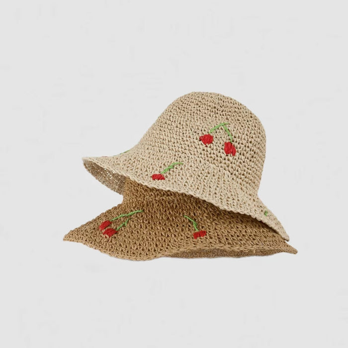 Two cherry straw hats are stacked together, showcasing their subtle differences in detail.