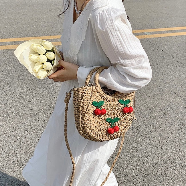 Model carrying a khaki Cherry Rattan Straw Bag handheld, easy for commuting and weekends.