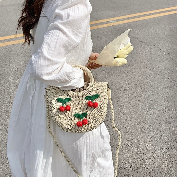 Model carrying a beige Cherry Rattan Straw Bag handheld, easy for commuting and weekends.