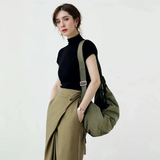 A model carrying the olive green chic ruched crescent bag on her shoulder showing the padded texture.