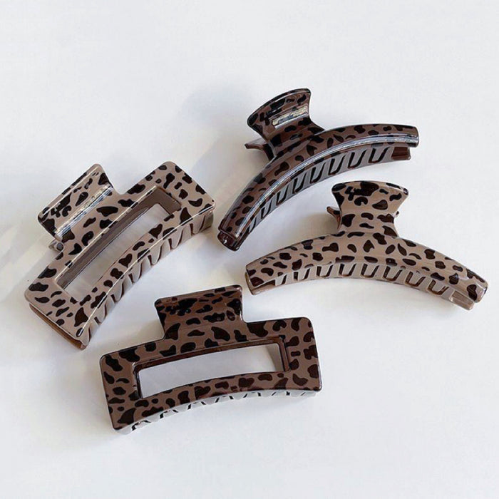 Front view of four Acrylic chocolate leopard print hair claws in various sizes and shapes.