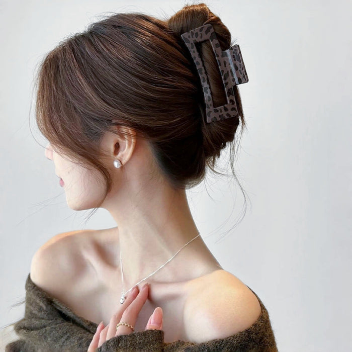 Model wearing a dark Chocolate Leopard Print Hair Claw in square shape.