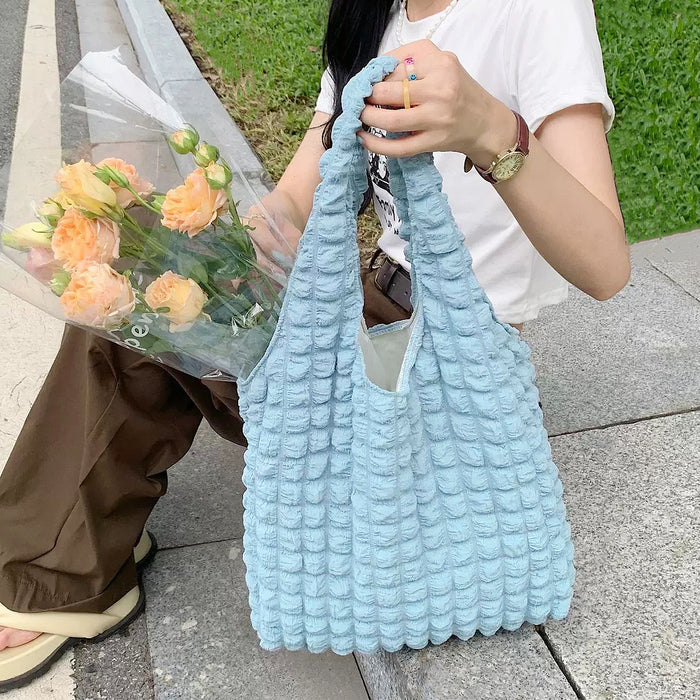 Model holding the light blue Cloud Puff Tote Bag, showing the soft bubble texture.