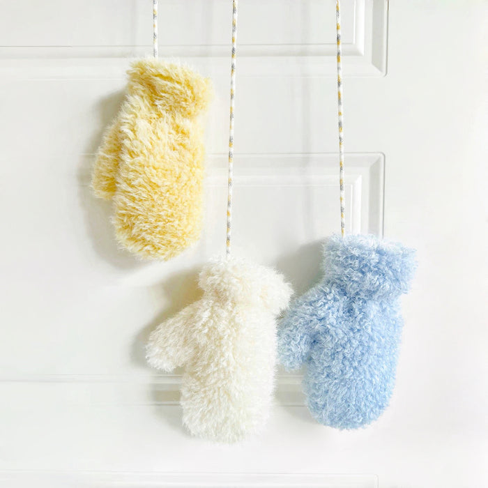 Cloud-touch fluffy gloves hanging in yellow, white, and blue; plush texture for cozy winter warmth.